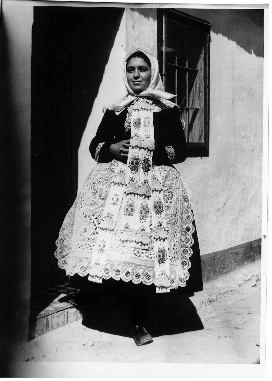 Svobodná dívka ve slavnostním kroji – molový fěrtoch a obojek s velkými „trutrovými“  vzory. Hlohovec, 50. léta 20. století
